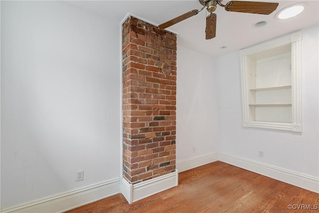 spare room featuring hardwood / wood-style floors, built in shelves, and ceiling fan