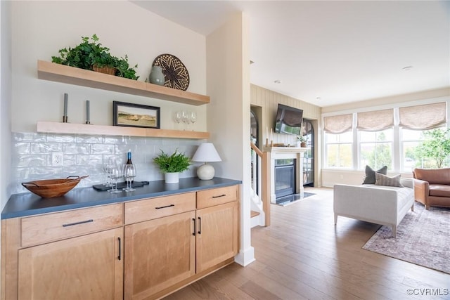 bar featuring light brown cabinetry, backsplash, and light wood-type flooring