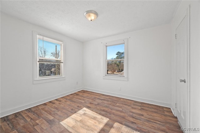 unfurnished room with dark hardwood / wood-style flooring and a textured ceiling