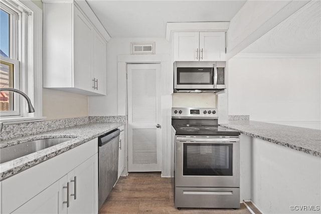 kitchen featuring sink, dark hardwood / wood-style flooring, stainless steel appliances, light stone countertops, and white cabinets