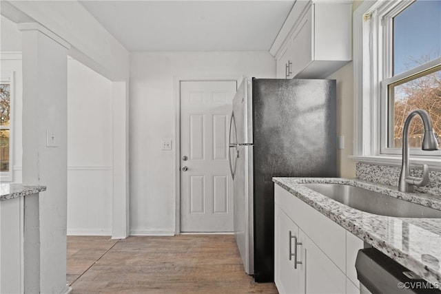 kitchen featuring stainless steel appliances, light stone countertops, sink, and white cabinets