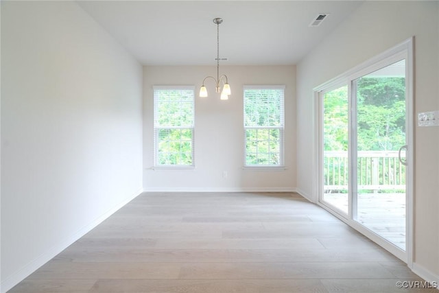 empty room featuring a notable chandelier and light hardwood / wood-style floors