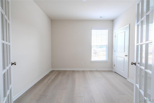 unfurnished room featuring french doors and light hardwood / wood-style floors