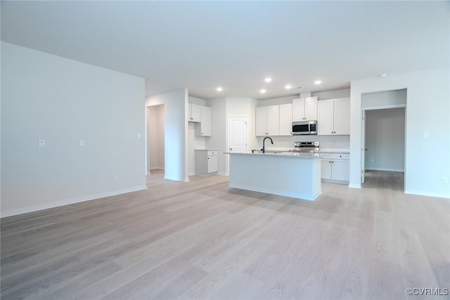 kitchen with sink, white cabinetry, a center island with sink, stainless steel appliances, and light hardwood / wood-style floors