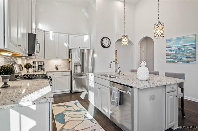 kitchen with a kitchen island with sink, white cabinetry, stainless steel appliances, and a kitchen breakfast bar