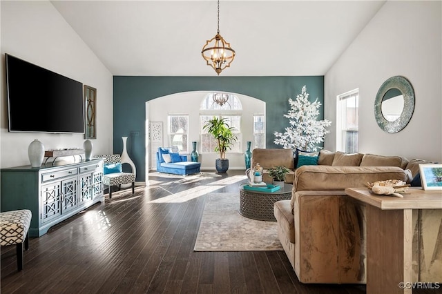 living room with dark hardwood / wood-style flooring, vaulted ceiling, and an inviting chandelier