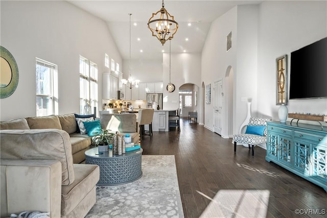 living room featuring dark wood-type flooring, a wealth of natural light, high vaulted ceiling, and a notable chandelier