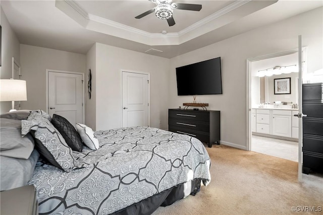 bedroom featuring crown molding, light carpet, ensuite bathroom, and a tray ceiling