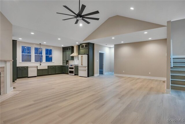 unfurnished living room featuring sink, light hardwood / wood-style flooring, ceiling fan, high vaulted ceiling, and a high end fireplace