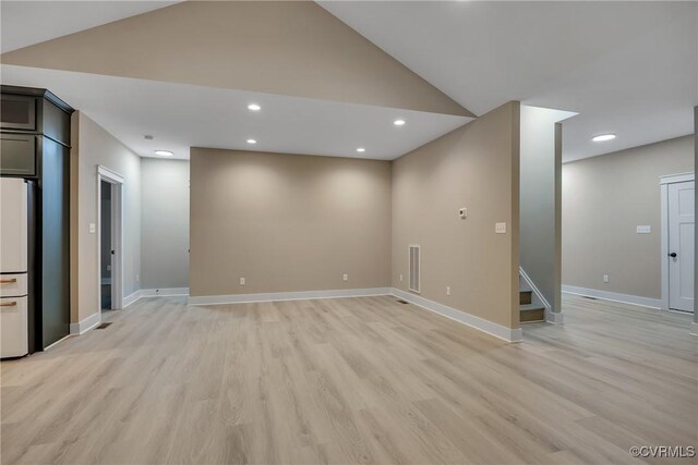 unfurnished living room featuring vaulted ceiling and light hardwood / wood-style flooring