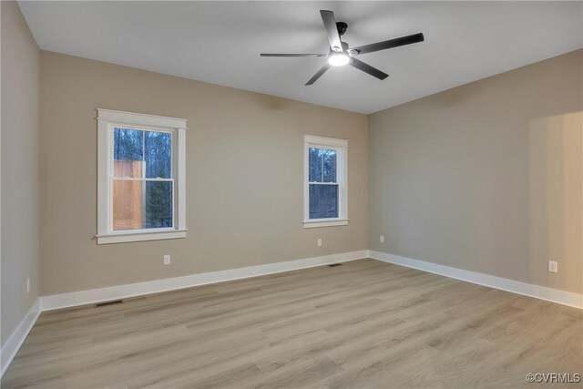 empty room featuring ceiling fan, a wealth of natural light, and light wood-type flooring