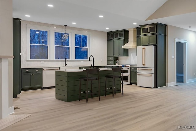 kitchen with wall chimney exhaust hood, a breakfast bar area, high end appliances, green cabinetry, and pendant lighting