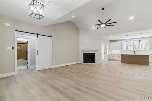 2280 Hensley Rd, Mineral, VA 23117 - unfurnished living room featuring a sink, ceiling fan, a barn door, light wood-style flooring, and a fireplace