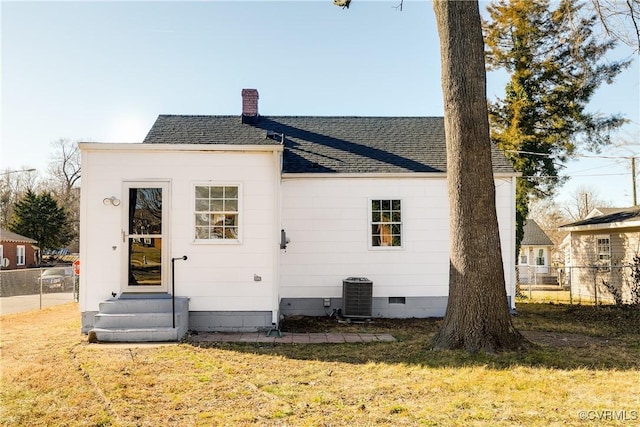 back of house featuring central AC unit and a lawn