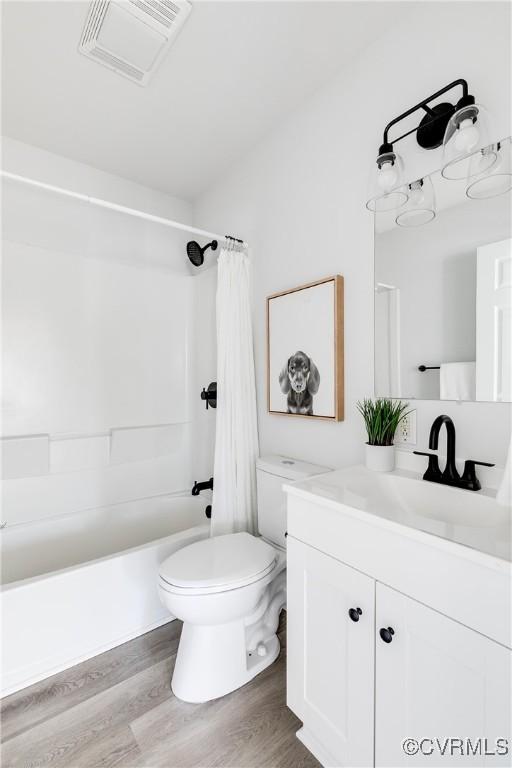 full bathroom with hardwood / wood-style flooring, vanity, toilet, and shower / tub combo