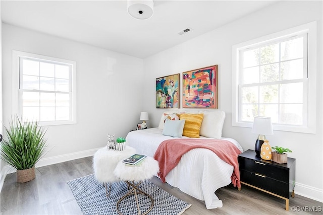 bedroom with multiple windows and hardwood / wood-style flooring