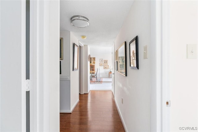 hall featuring dark wood-type flooring and a textured ceiling