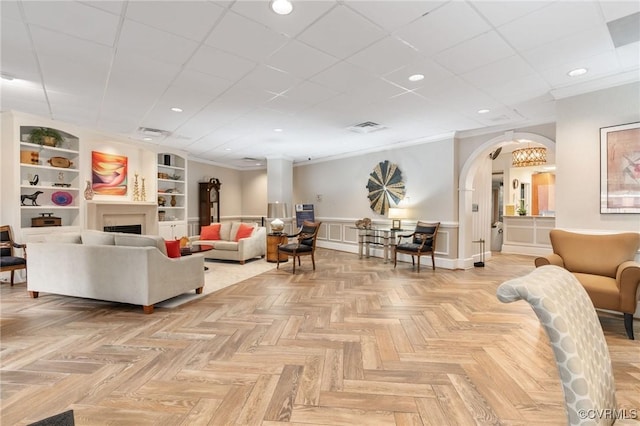 living room featuring crown molding, light parquet flooring, and built in shelves