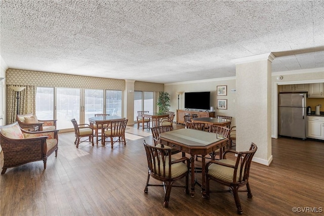 dining space featuring ornamental molding, wood-type flooring, and a textured ceiling