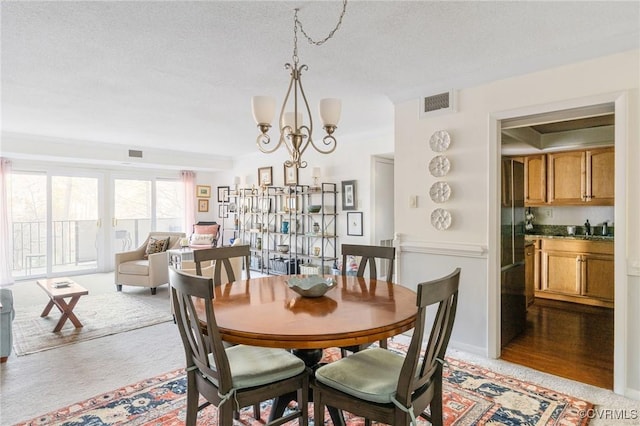 dining space with sink, a textured ceiling, and a chandelier