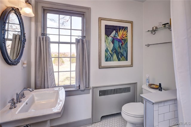 bathroom with radiator, sink, tile patterned floors, and toilet