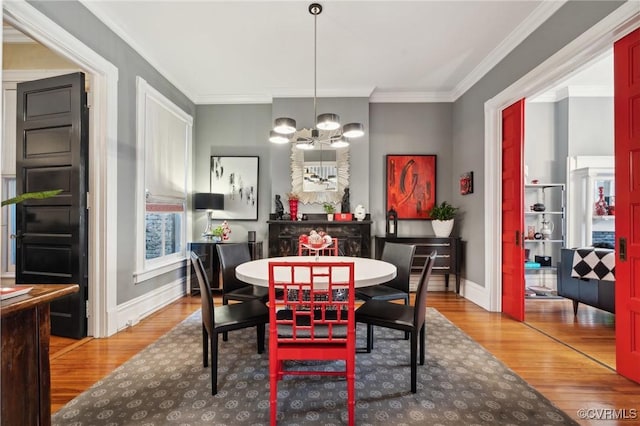 dining room featuring wood-type flooring, crown molding, and a chandelier