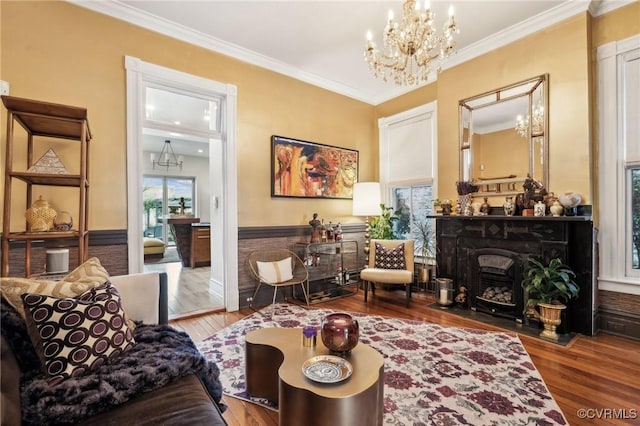 living area featuring crown molding, hardwood / wood-style floors, and a notable chandelier