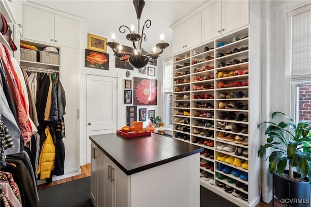 spacious closet featuring dark hardwood / wood-style flooring and a chandelier