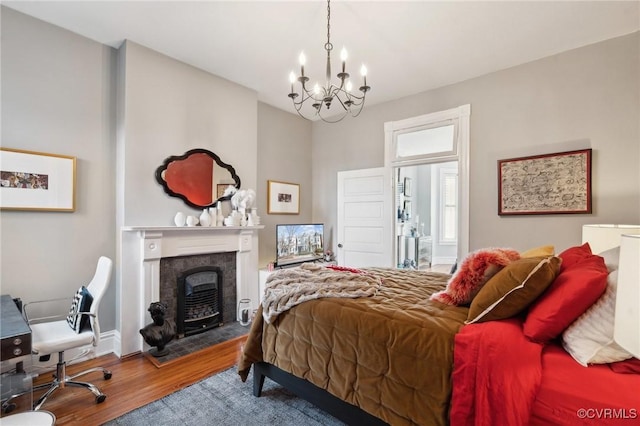 bedroom featuring hardwood / wood-style flooring, a tiled fireplace, and a chandelier