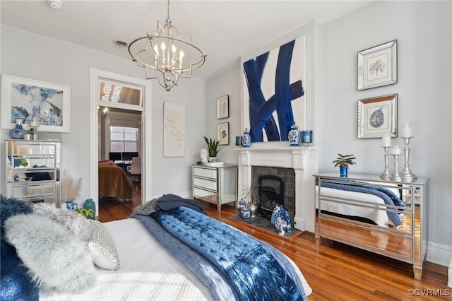 bedroom with hardwood / wood-style flooring, a fireplace, and a chandelier