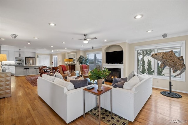 living room with crown molding, plenty of natural light, ceiling fan, and light hardwood / wood-style flooring