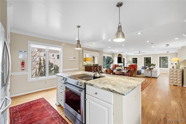 kitchen with appliances with stainless steel finishes, pendant lighting, white cabinets, a kitchen island with sink, and light hardwood / wood-style flooring