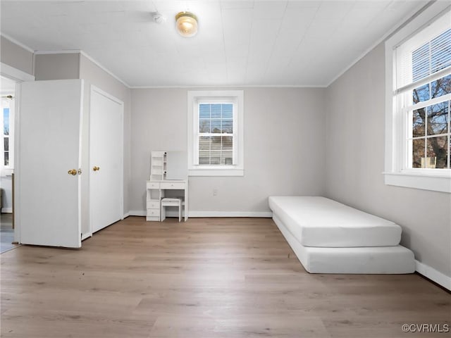 unfurnished bedroom featuring multiple windows, ornamental molding, and light hardwood / wood-style floors