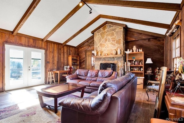 living room with beam ceiling, a stone fireplace, french doors, and wooden walls