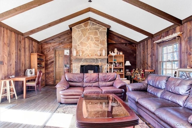 living room with lofted ceiling with beams, wood walls, a stone fireplace, and wood-type flooring