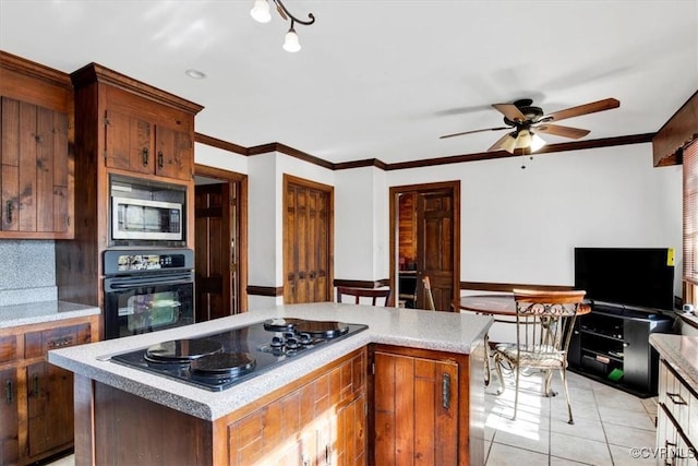 kitchen with a kitchen island, black appliances, ceiling fan, light tile patterned floors, and crown molding