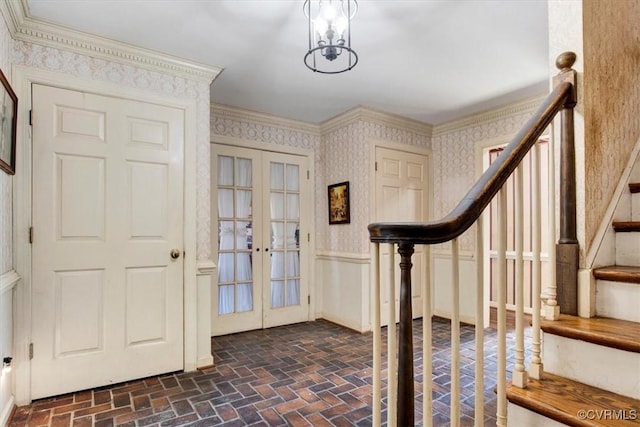 entryway featuring crown molding, french doors, and an inviting chandelier