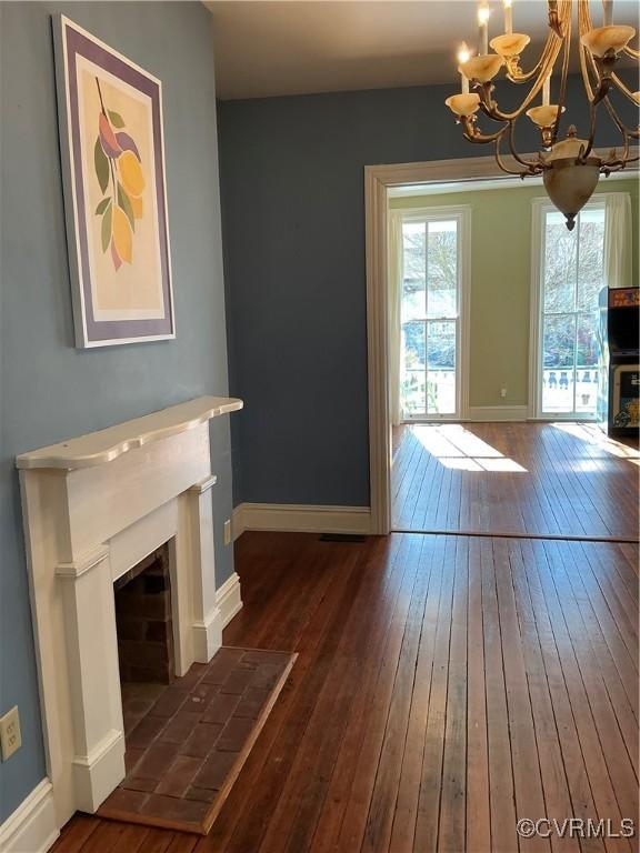 unfurnished living room with an inviting chandelier and dark hardwood / wood-style floors