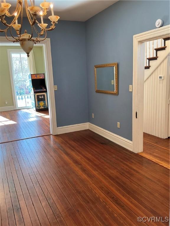 unfurnished living room with dark hardwood / wood-style floors and a notable chandelier