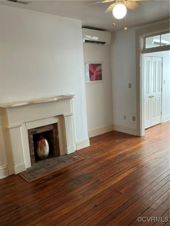 unfurnished living room featuring ceiling fan, dark hardwood / wood-style floors, and an AC wall unit