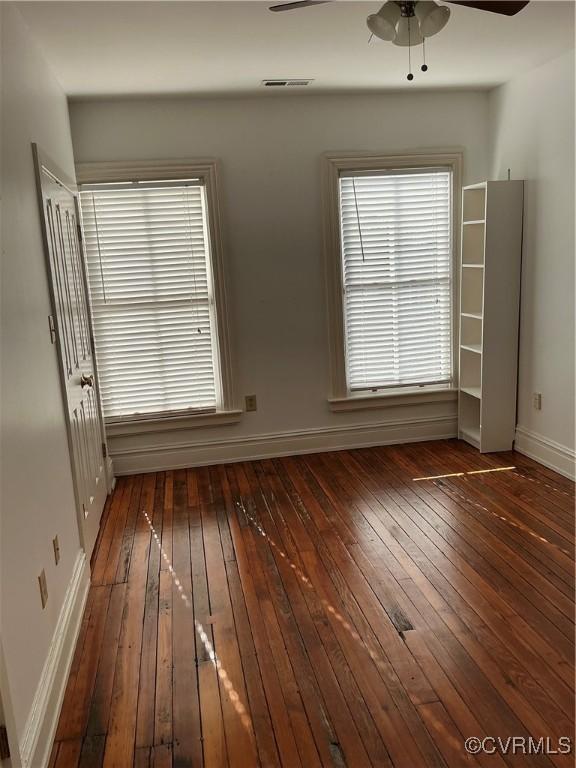 spare room featuring plenty of natural light, dark wood-type flooring, and ceiling fan