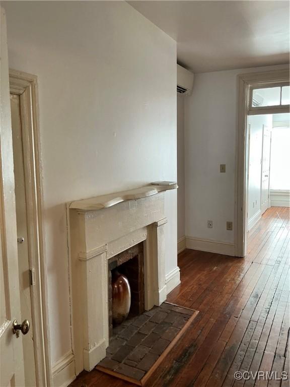 unfurnished living room with dark wood-type flooring and a wall unit AC