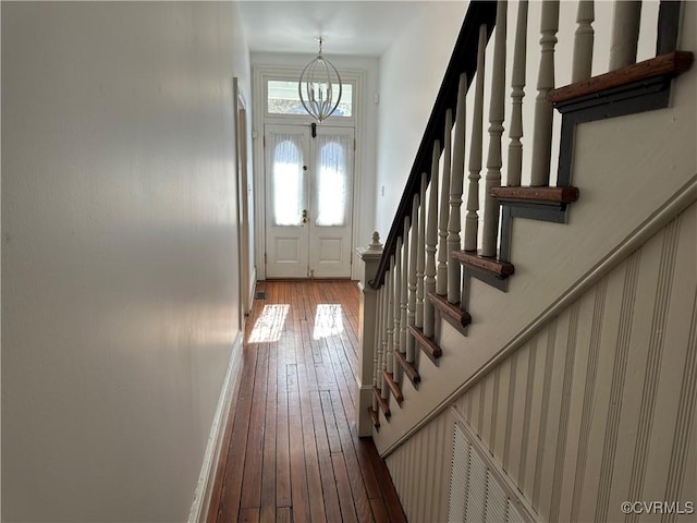 doorway to outside with stairs, a chandelier, and hardwood / wood-style flooring