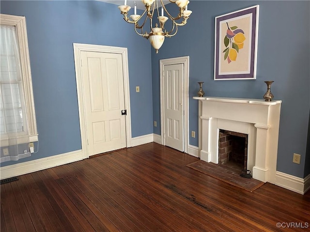 unfurnished living room featuring baseboards, hardwood / wood-style floors, a fireplace with flush hearth, and an inviting chandelier