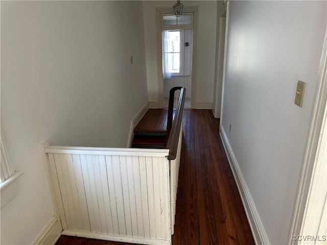 corridor featuring baseboards and dark wood-type flooring