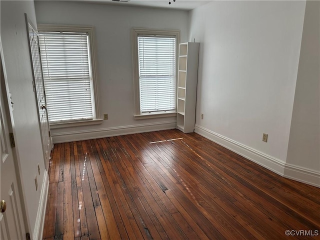 empty room featuring a wealth of natural light, baseboards, and hardwood / wood-style floors