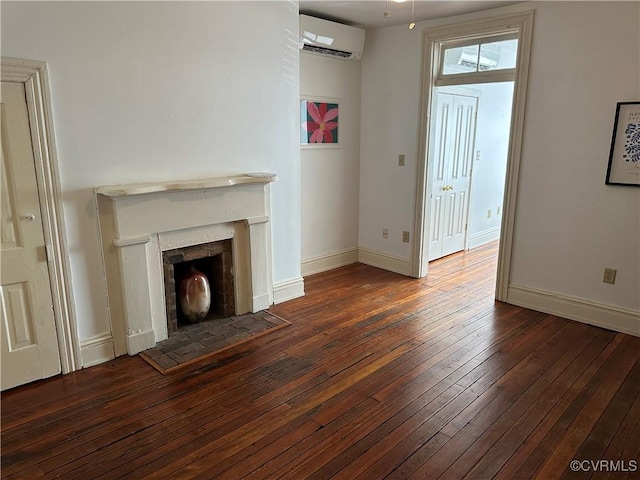 unfurnished living room with a wall unit AC, a fireplace, hardwood / wood-style flooring, and baseboards