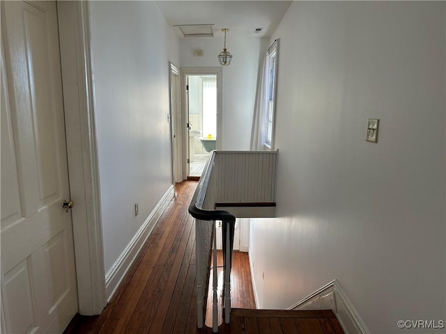 corridor featuring attic access, baseboards, and hardwood / wood-style floors