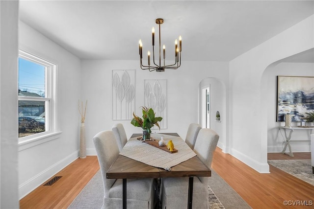 dining area with hardwood / wood-style flooring and a notable chandelier