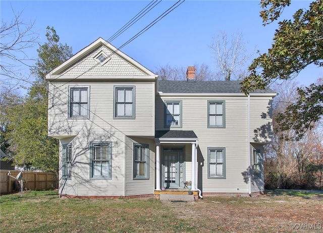 view of front facade with a front lawn, fence, and a chimney